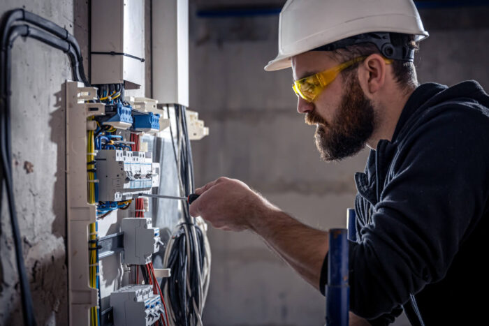 a-male-electrician-works-in-a-switchboard-with-an-electrical-connecting-cable