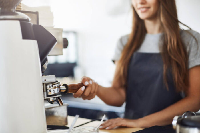 close-up-of-female-barista-grinding-coffee-to-make-a-perfect-espresso-cup-in-a-bright-cafe-on-a-sunny-winter-day