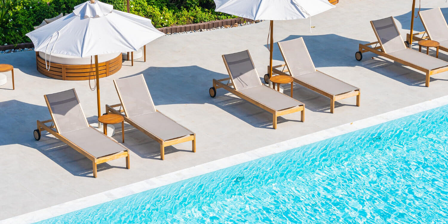 umbrella-and-deck-chair-around-outdoor-swimming-pool-in-hotel-resort-nearly-sea-beach-ocean