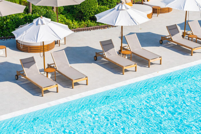 umbrella-and-deck-chair-around-outdoor-swimming-pool-in-hotel-resort-nearly-sea-beach-ocean